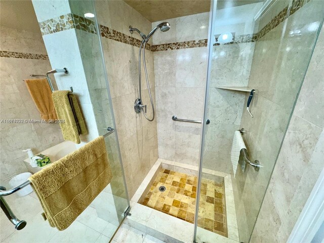 bathroom with a shower with shower door and tile walls