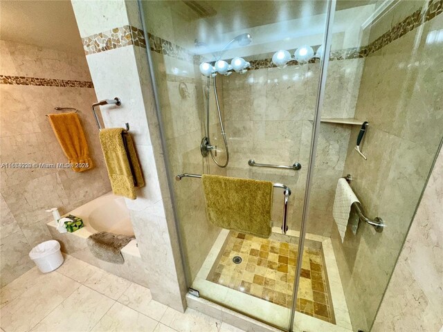 bathroom featuring tile walls and separate shower and tub