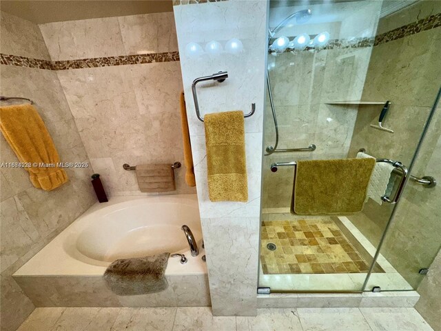 bathroom with tile walls and separate shower and tub