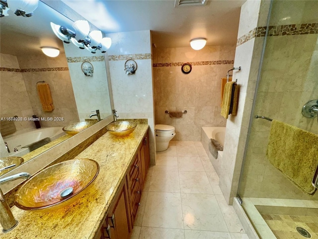 full bath featuring toilet, a bathing tub, a sink, a shower stall, and tile walls