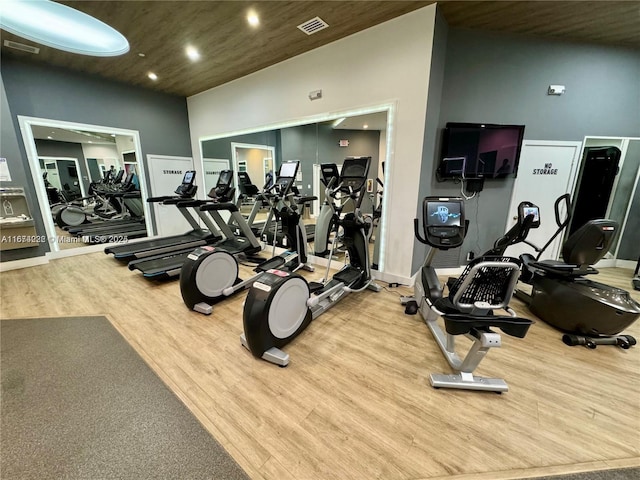 workout area featuring visible vents, vaulted ceiling, wood finished floors, and recessed lighting