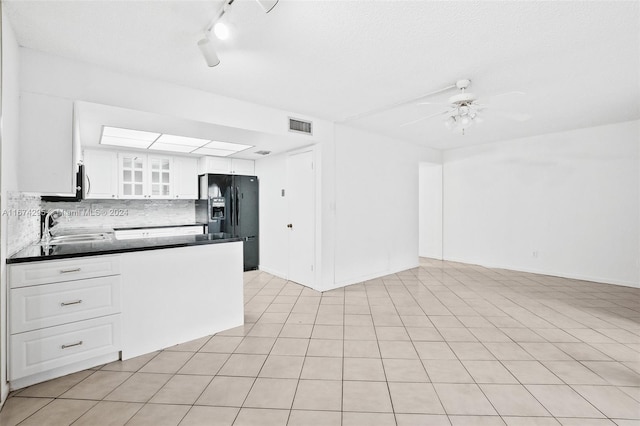 kitchen featuring ceiling fan, black fridge, white cabinetry, light tile patterned floors, and backsplash