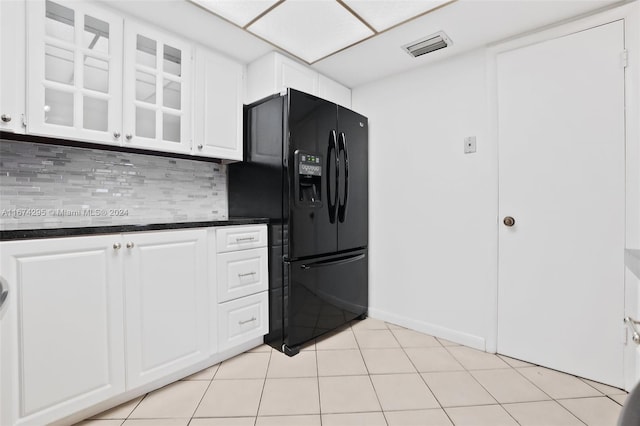 kitchen featuring decorative backsplash, light tile patterned flooring, white cabinets, and black fridge with ice dispenser