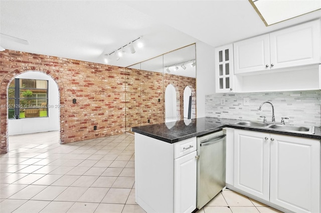 kitchen with white cabinets, sink, stainless steel dishwasher, and brick wall