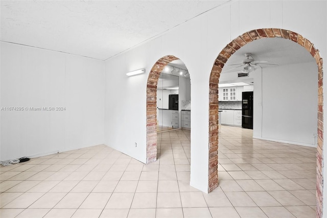 empty room with ceiling fan, light tile patterned floors, and a textured ceiling