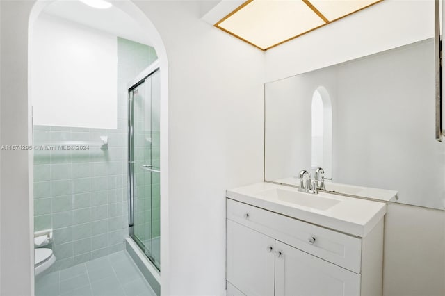 bathroom featuring an enclosed shower, vanity, tile patterned flooring, and toilet