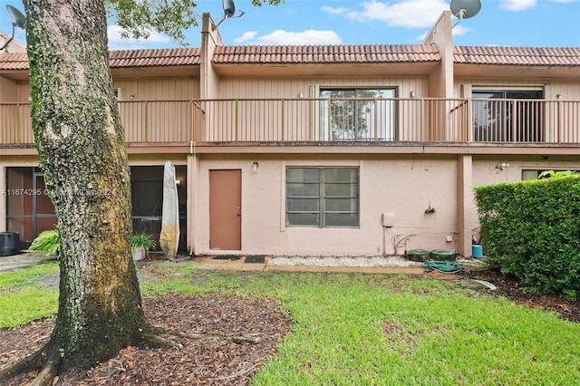 back of property featuring a balcony and a lawn