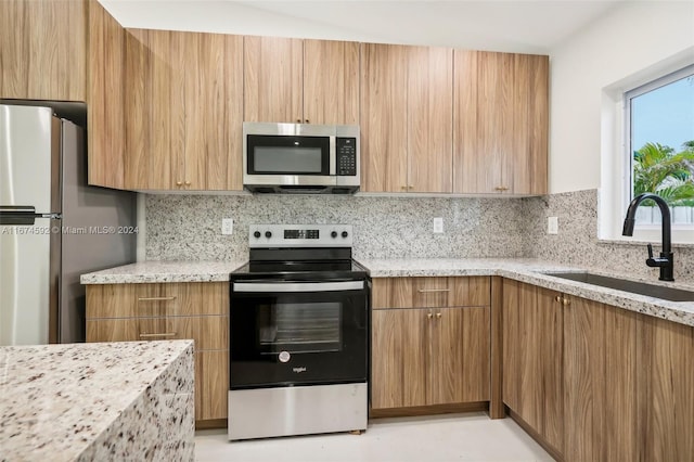 kitchen featuring light stone countertops, sink, stainless steel appliances, and backsplash