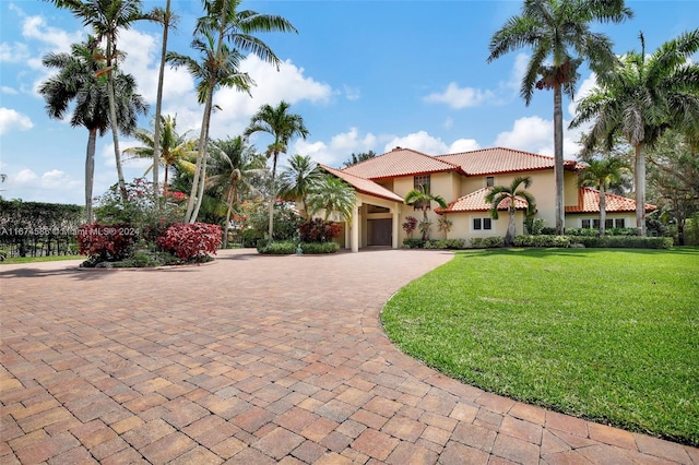 mediterranean / spanish-style house featuring a front yard and a garage