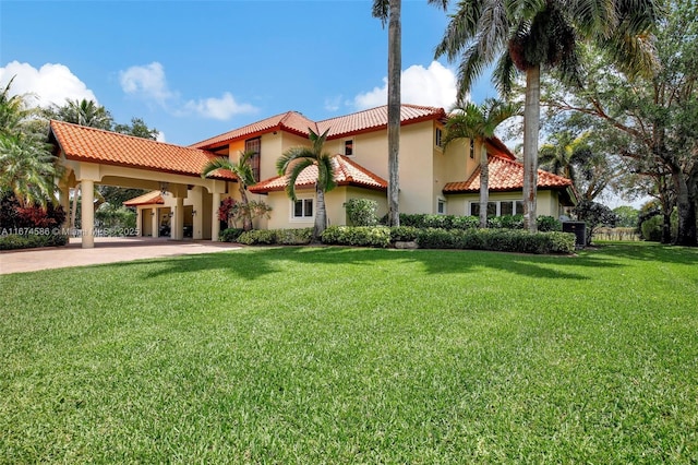 mediterranean / spanish house featuring driveway, a tiled roof, a front lawn, and stucco siding