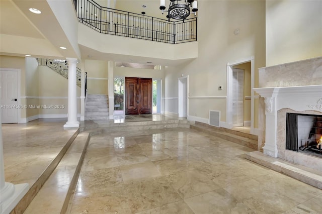 foyer featuring a high end fireplace, visible vents, baseboards, marble finish floor, and stairway