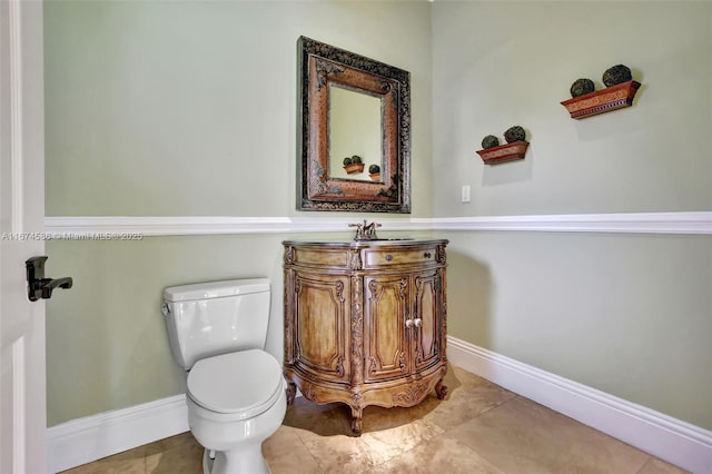 half bath featuring tile patterned floors, vanity, toilet, and baseboards