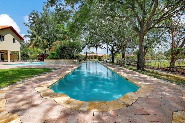 outdoor pool with fence and a patio