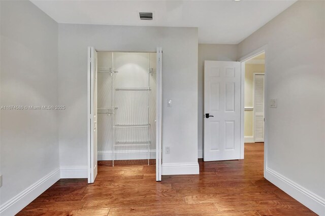 unfurnished bedroom featuring a closet and hardwood / wood-style floors