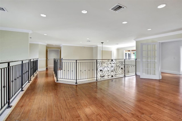 unfurnished room featuring wood-type flooring, visible vents, and crown molding