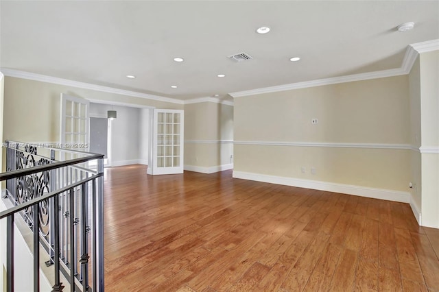 unfurnished room with baseboards, light wood-style flooring, visible vents, and crown molding