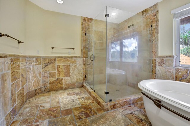 bathroom with tile walls and independent shower and bath