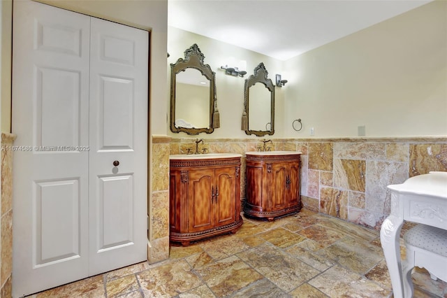 bathroom featuring stone tile floors, tile walls, a closet, and vanity