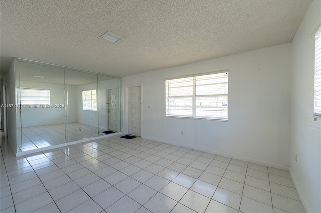 unfurnished bedroom with light tile patterned flooring, a closet, and a textured ceiling