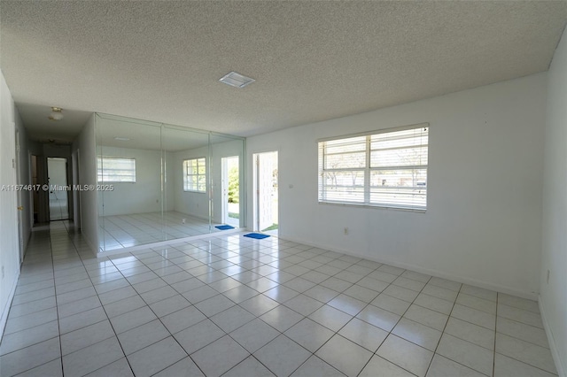 tiled empty room with a textured ceiling