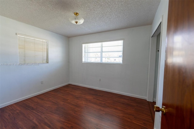 unfurnished room with dark wood-type flooring and a textured ceiling