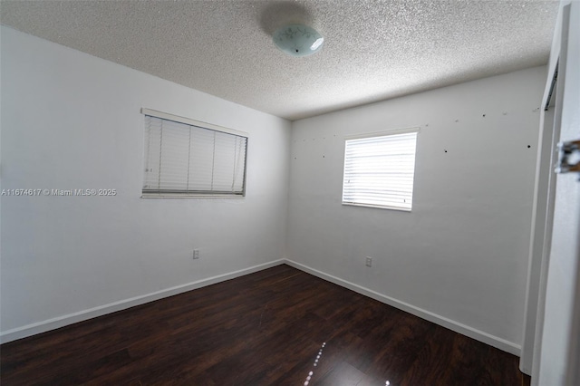 unfurnished room featuring a textured ceiling and dark hardwood / wood-style flooring