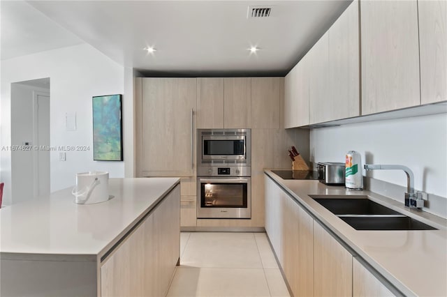 kitchen featuring light tile patterned floors, light brown cabinets, stainless steel appliances, and sink