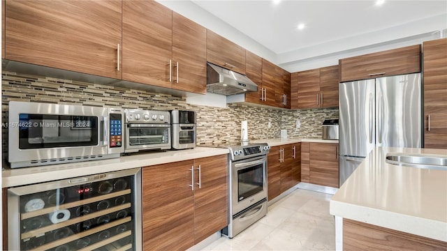 kitchen featuring exhaust hood, beverage cooler, stainless steel appliances, and backsplash