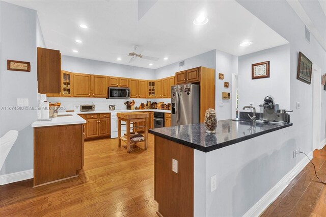 kitchen with ceiling fan, sink, kitchen peninsula, appliances with stainless steel finishes, and light wood-type flooring