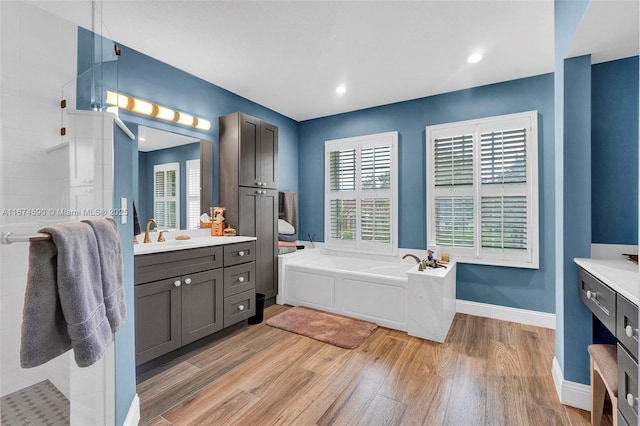 bathroom with hardwood / wood-style flooring, vanity, a tub, and a wealth of natural light