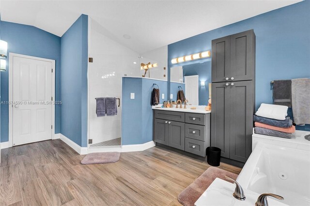 bathroom featuring vanity, hardwood / wood-style flooring, vaulted ceiling, and independent shower and bath