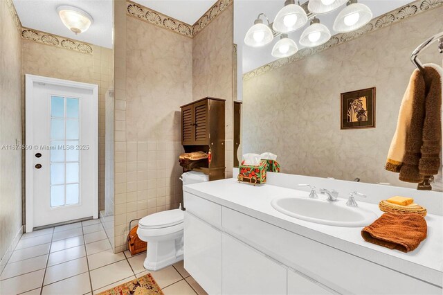 bathroom with tile patterned flooring, vanity, tile walls, and toilet