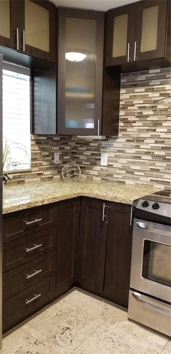 kitchen with range, decorative backsplash, light stone countertops, stainless steel refrigerator with ice dispenser, and exhaust hood