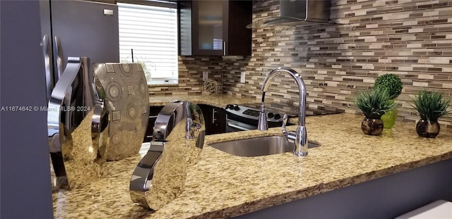 kitchen with light stone counters, stainless steel range, dark brown cabinetry, and tasteful backsplash