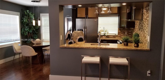 kitchen featuring stacked washing maching and dryer, tasteful backsplash, dark brown cabinets, light stone counters, and appliances with stainless steel finishes