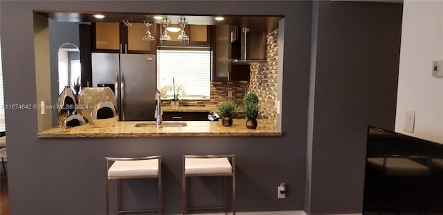 interior details with light stone countertops, backsplash, sink, and stacked washer / drying machine