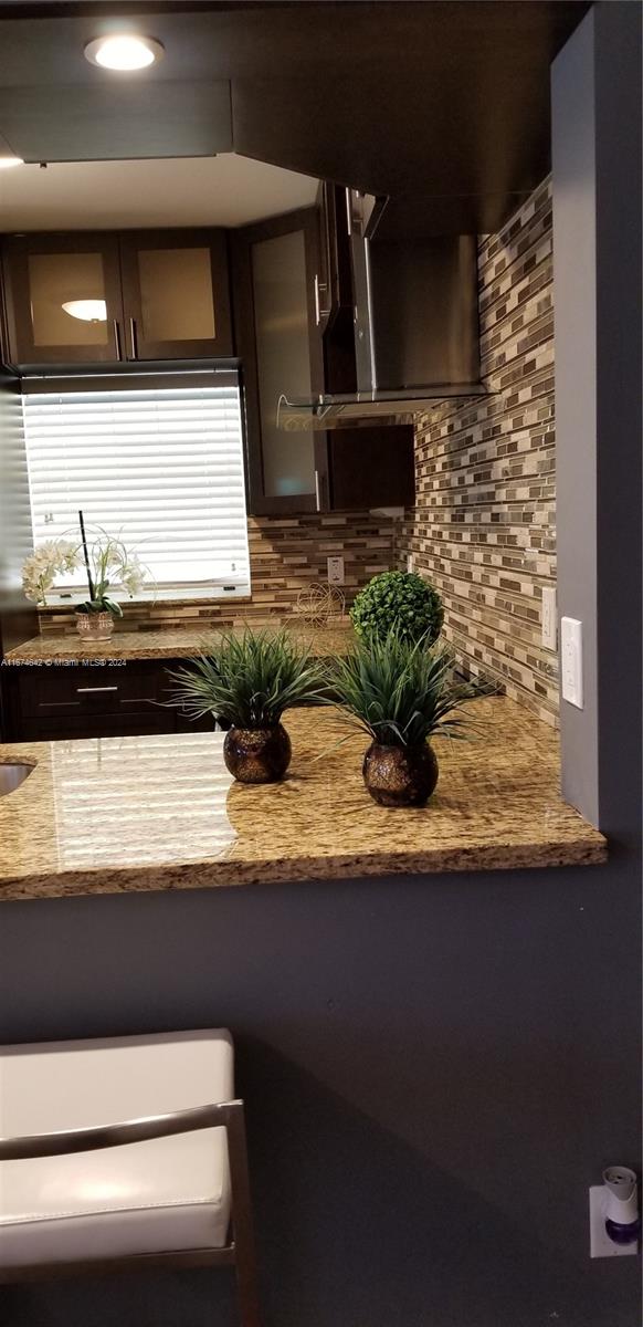 kitchen with light stone countertops, backsplash, and sink