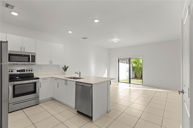 kitchen featuring kitchen peninsula, stainless steel appliances, sink, white cabinetry, and light tile patterned flooring