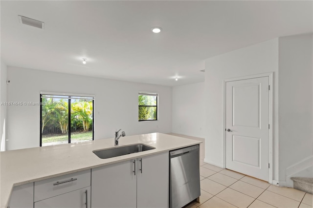 kitchen with stainless steel dishwasher, light tile patterned flooring, white cabinets, and sink