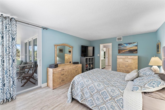 bedroom featuring hardwood / wood-style floors, access to exterior, and a textured ceiling