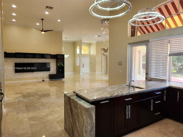 kitchen with light stone countertops, crown molding, an inviting chandelier, and sink