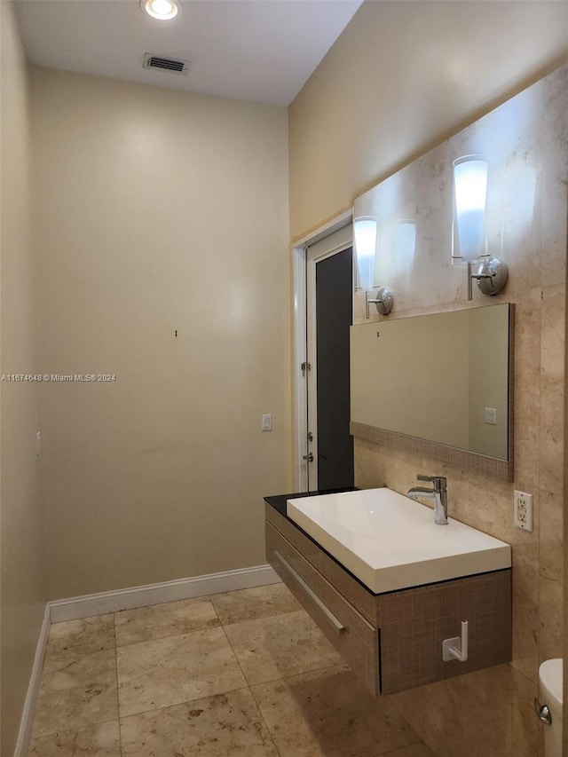 bathroom with vanity, tile walls, and toilet