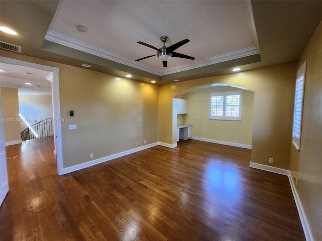 unfurnished living room featuring ornamental molding, dark wood-type flooring, and a raised ceiling