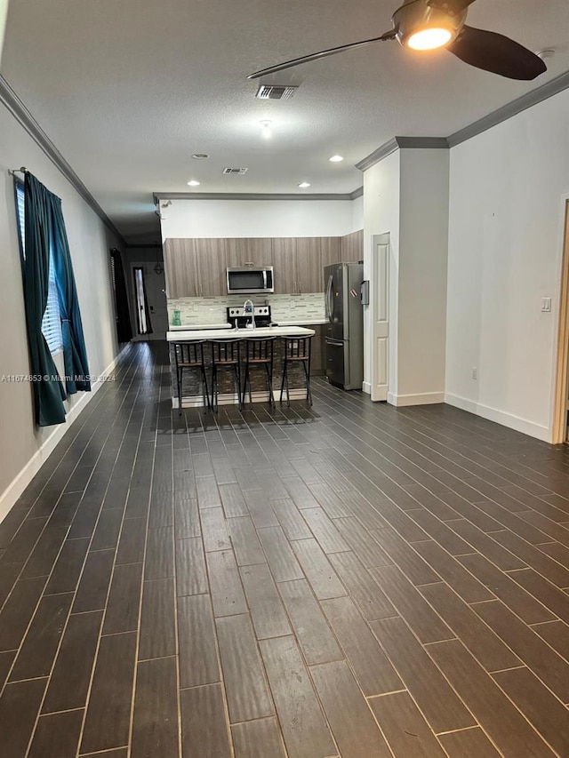 kitchen with dark hardwood / wood-style floors, appliances with stainless steel finishes, and ornamental molding