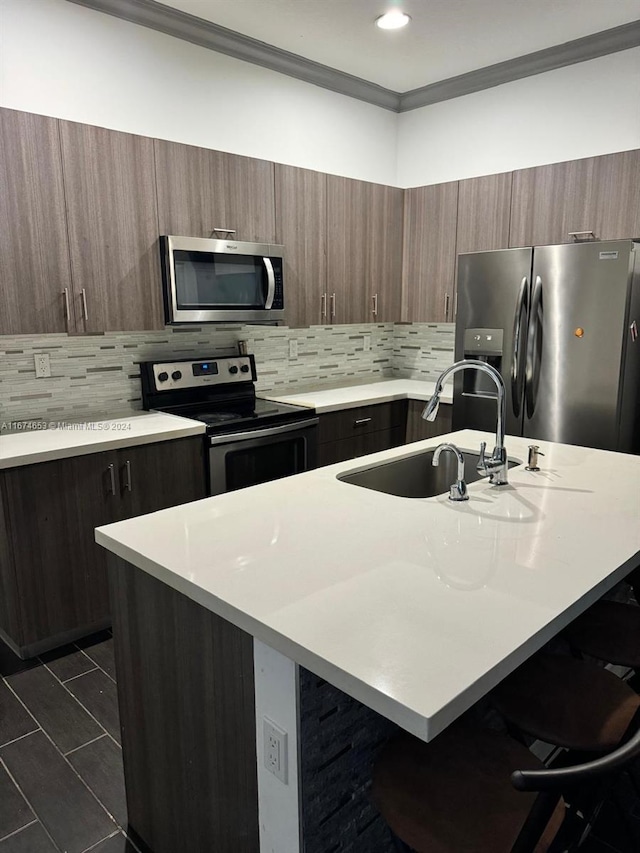 kitchen featuring appliances with stainless steel finishes, decorative backsplash, a breakfast bar area, and a center island with sink