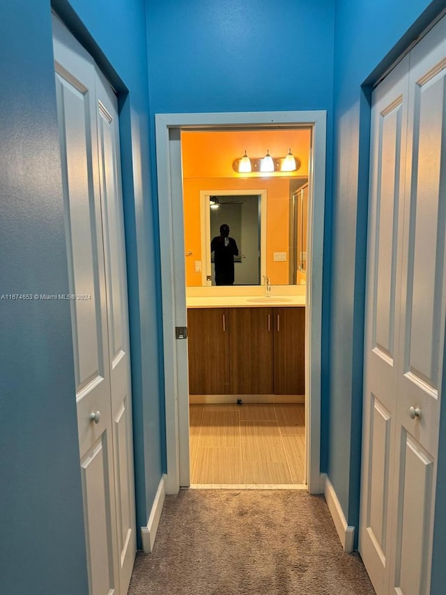 hallway with carpet floors and sink