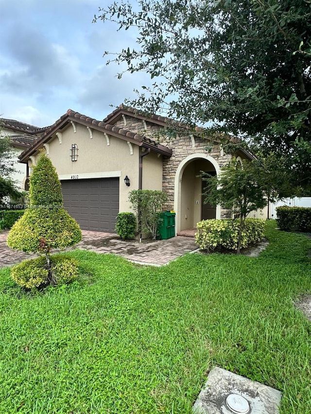 mediterranean / spanish house featuring a garage and a front lawn