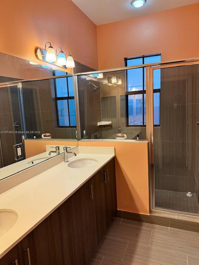 bathroom featuring a shower with door and vanity