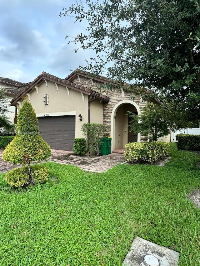 mediterranean / spanish home featuring a garage and a front yard