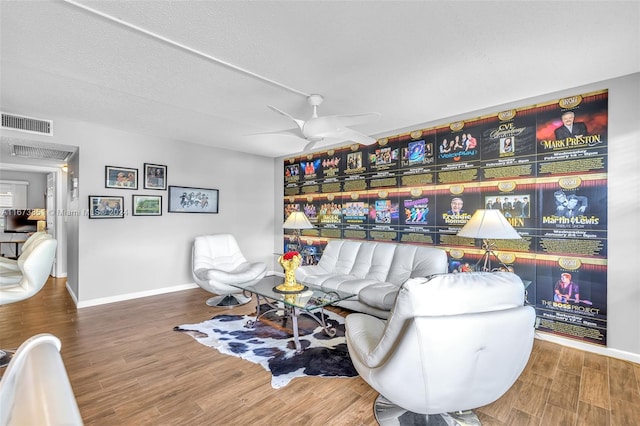 living room featuring wood-type flooring, a textured ceiling, and ceiling fan